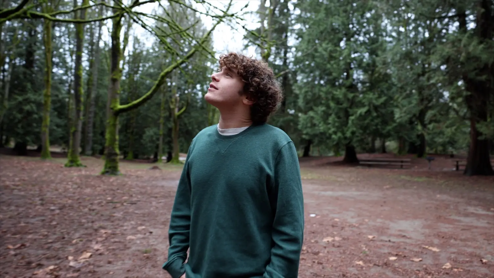 Jonah Kessler-Cohen stands pensively in a forest, behind the scenes of a Moose Not Meese video