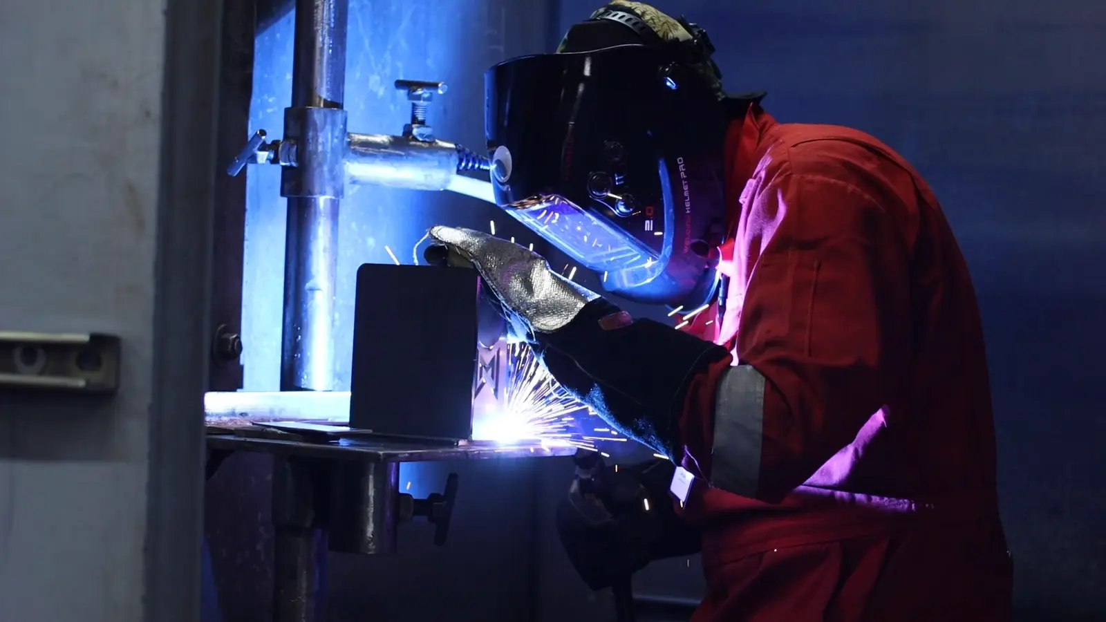 Still from video, student in protective gear welds in SkillsUSA competition, sparks flying
